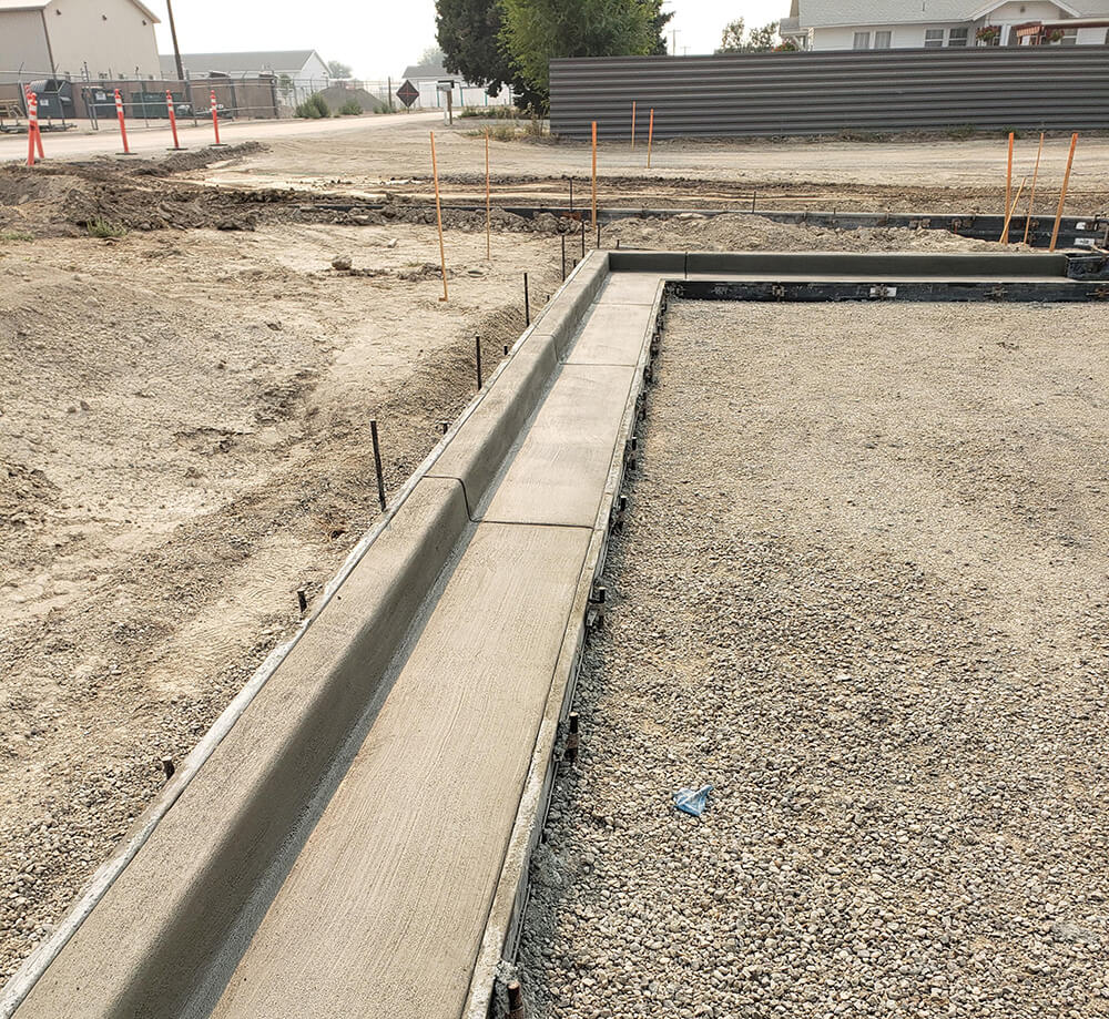 Road surface under construction, concrete curb finished before asphalt pour.