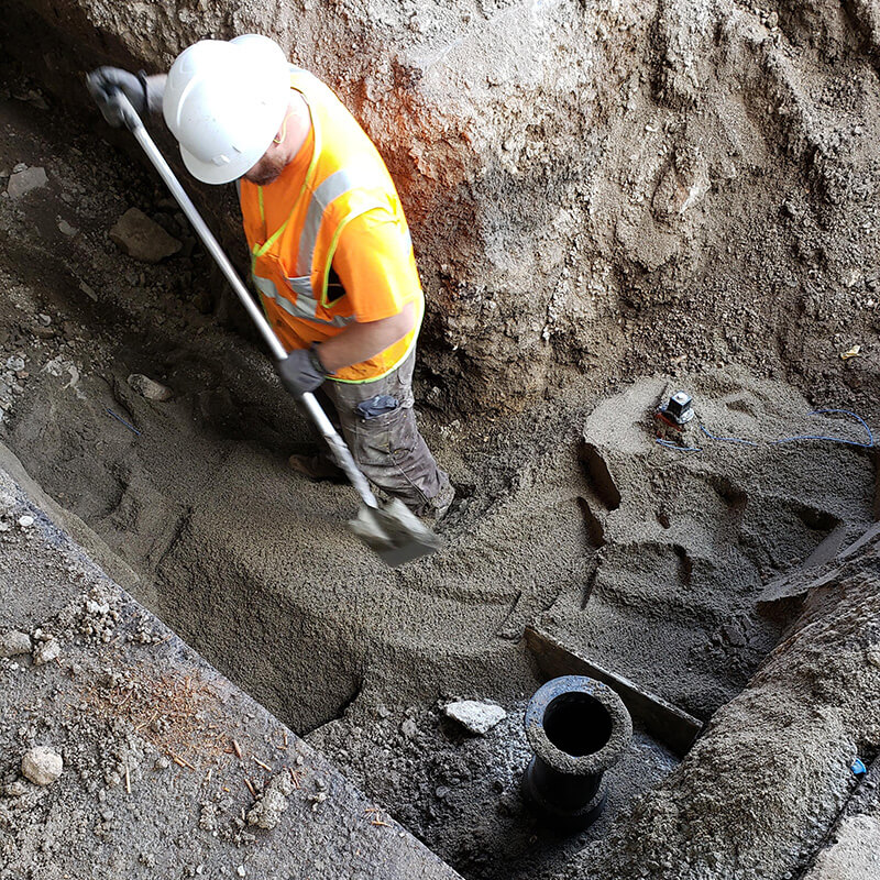 Tradesmen with shovel preparing area for underground utility work.