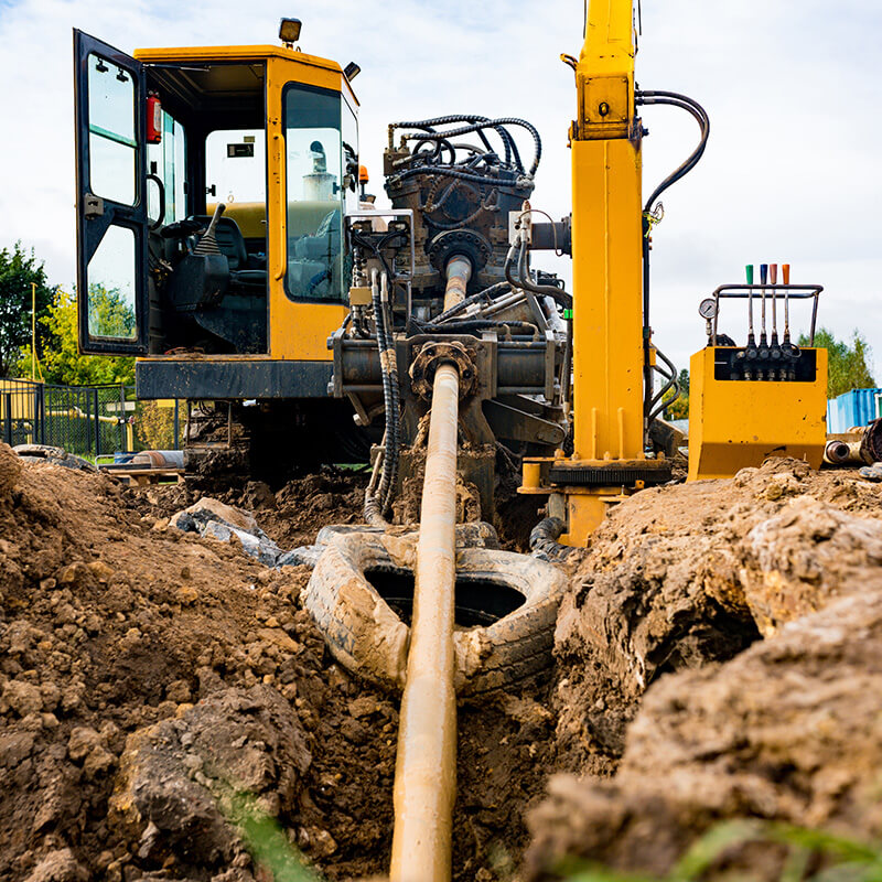 Tractor used for horizontal direction digging in use by an earthen ditch.